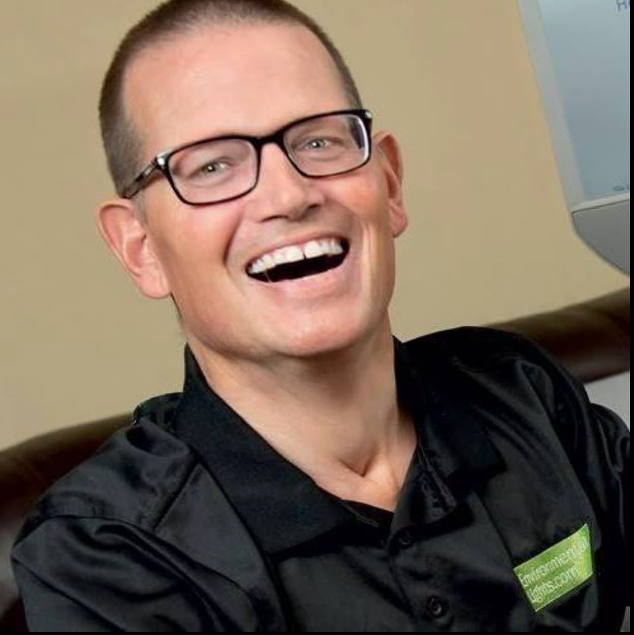 Light-skinned man with black framed glasses and short hair smiling at camera